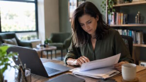 Imagem mostra mulher analisando papéis em seu escritório, para simbolizar como funciona o Simples Nacional para psicólogos